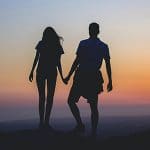 Pareja dándose la mano al atardecer