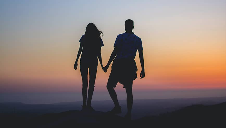 Foto de una pareja dándose la mano al atardecer